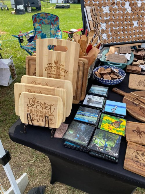 A display of wooden kitchen items, including cutting boards and utensils, at an outdoor market.