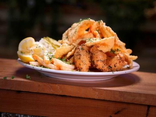 A plate of crispy fried fish and chips, garnished with lemon wedges and parsley.