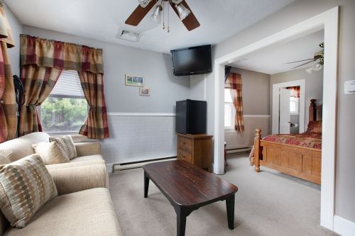 Cozy room with a sofa, coffee table, TV, and a separate bedroom area featuring a wooden bed and warm decor.