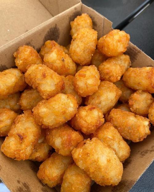 A box filled with golden, crispy tater tots piled high.