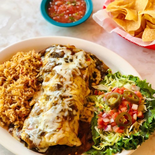 A plate of enchiladas topped with cheese, served with rice, a fresh salad, salsa, and a side of tortilla chips.