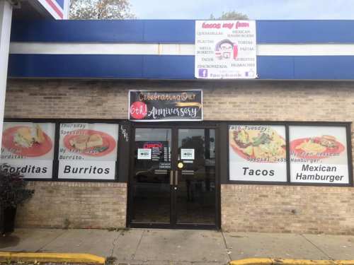 Exterior of a restaurant featuring a sign for tacos, burritos, and hamburgers, with a "Celebrating Our 6th Anniversary" banner.