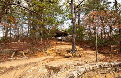 A trail junction with signs for Balanced Rock Trail, Hemlock Lodge, and Laurel Ridge Trail, surrounded by trees and autumn foliage.