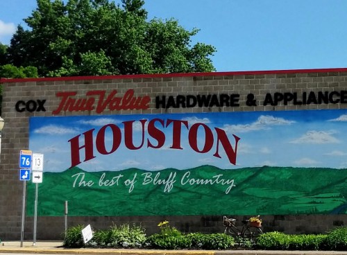 Mural on a hardware store wall featuring "HOUSTON" and scenic Bluff Country landscape.
