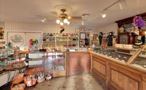 A cozy vintage candy shop with wooden counters, colorful jars, and whimsical decorations on the walls.