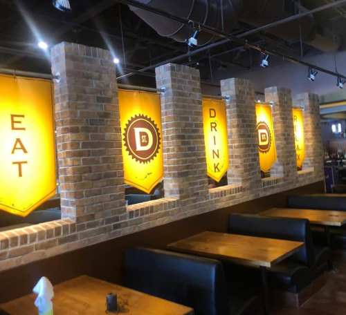 Interior of a restaurant featuring brick walls and yellow banners with the words "EAT," "DRINK," and "RELAX."