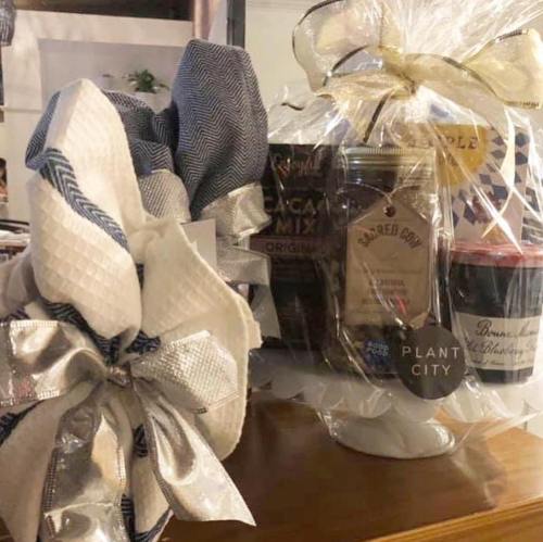 A decorative gift arrangement with wrapped items, including snacks and a jar, tied with elegant bows.