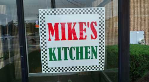 Sign on a window reading "MIKE'S KITCHEN" in red and green letters with a checkered border.