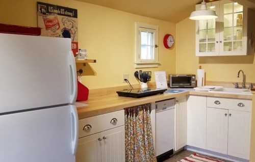 Bright kitchen with yellow walls, white cabinets, wooden countertops, and a cozy decor featuring a vintage poster.