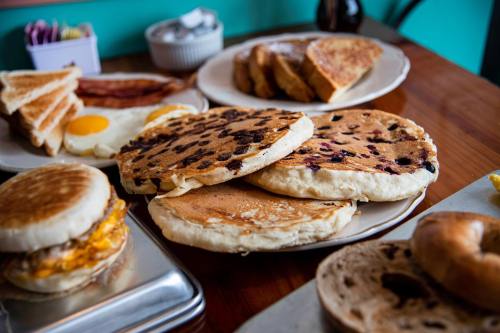 A table spread with various breakfast items, including pancakes, toast, eggs, and a bagel.