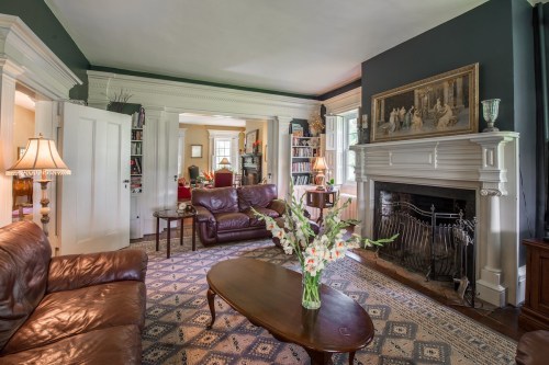 Cozy living room with leather sofas, a coffee table, a fireplace, and a vase of flowers on the table.