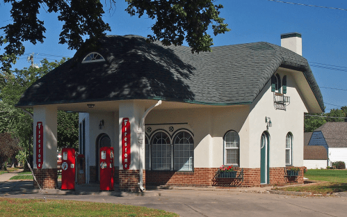 Historic gas station with a unique architectural design, featuring a curved roof and vintage red gas pumps.