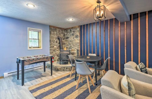 Cozy living space with a stone fireplace, dining table, foosball table, and modern seating against a blue wall.