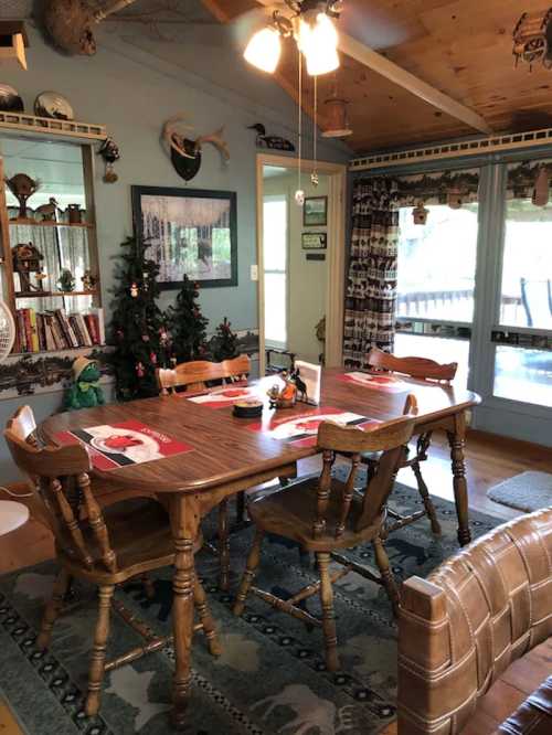 Cozy dining room with a wooden table, chairs, and holiday decorations, including a small Christmas tree.