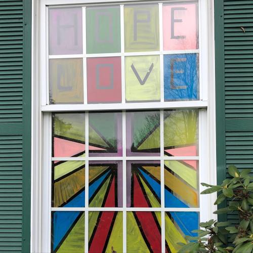 Colorful window painting featuring the words "HOPE" and "LOVE" with vibrant rays of color radiating outward.