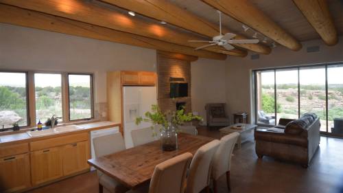 A modern kitchen and dining area with wooden beams, a large window, and a view of the outdoors.