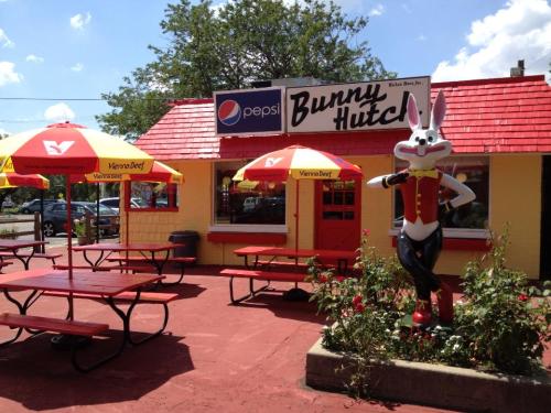 A colorful fast-food restaurant called Bunny Hutch, featuring outdoor seating and a cartoon rabbit statue.