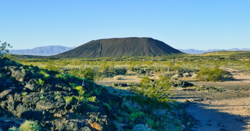 Amboy Crater in Southern California's Mojave Desert is surrounded by summer blooms and greenery.