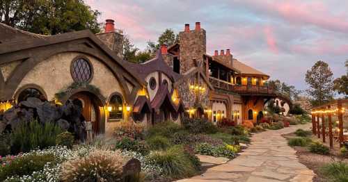 A whimsical, fairy-tale style building with unique architecture, surrounded by colorful gardens and a stone pathway.