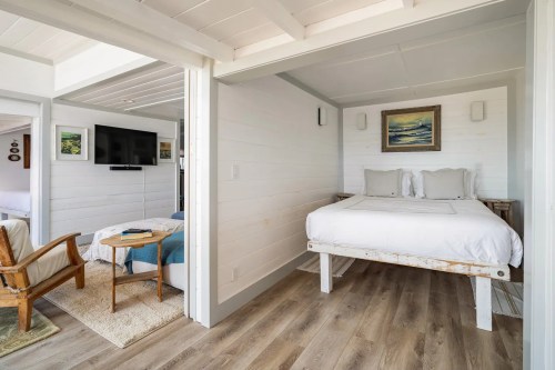A bright, modern bedroom with a bed, wooden furniture, and a cozy atmosphere, featuring light-colored walls and flooring.