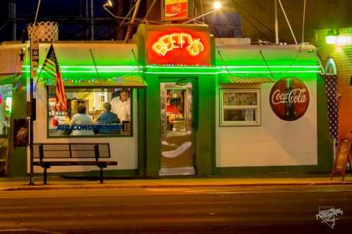 A brightly lit diner named "Beef's" with a Coca-Cola sign, featuring a bench outside and an open sign in the window.