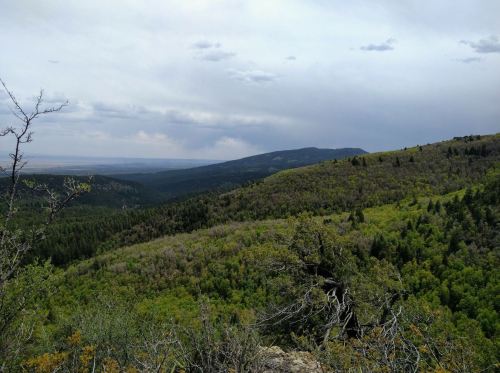 A panoramic view of a lush green mountain landscape under a cloudy sky.