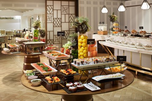 A lavish buffet display featuring a variety of colorful dishes, fruits, and desserts on elegant tables.
