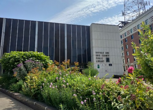 Exterior of the Buffalo and Erie County Public Library, featuring a landscaped garden with colorful flowers in the foreground.