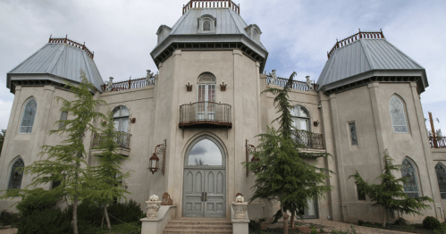 A large, ornate mansion with a unique architectural design, featuring turret-like towers and decorative windows.