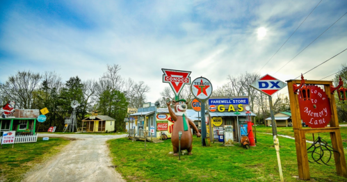 A nostalgic roadside scene featuring vintage gas station signs and a large bear statue in a quaint setting.