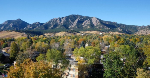 Scenic view of mountains with autumn foliage and a clear blue sky in the background.