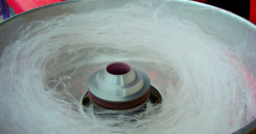 A close-up of a cotton candy machine, with fluffy strands of cotton candy swirling around a central cone.