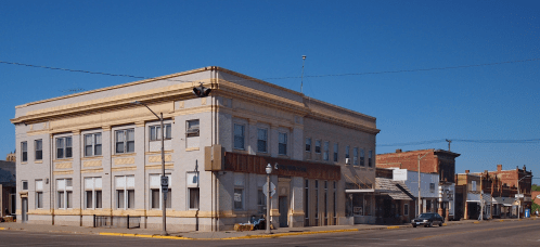 Historic brick building on a street corner, featuring decorative elements and a clear blue sky above.
