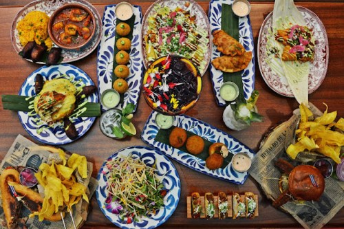 A vibrant spread of various dishes, including salads, snacks, and desserts, beautifully arranged on decorative plates.