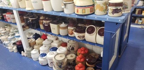 A display of various decorative jars and containers on shelves, featuring different colors and designs.