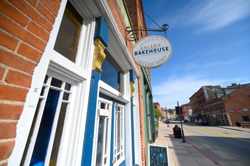 Exterior of Galena Bakehouse with a sign hanging above, featuring brick buildings and a clear blue sky in the background.