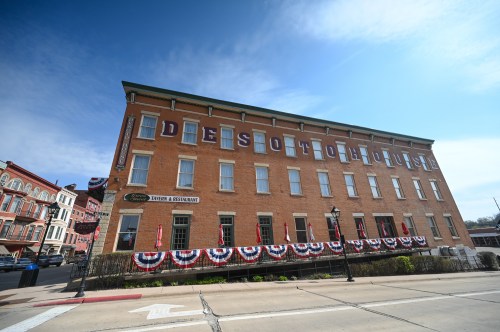Historic DeSoto House Hotel with patriotic bunting, set against a clear blue sky.