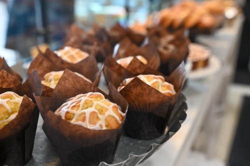 A display of freshly baked muffins with decorative icing, wrapped in brown paper liners.