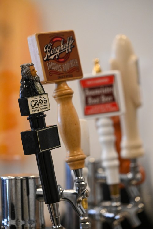 A row of beer taps featuring various brand logos and unique handles in a bar setting.