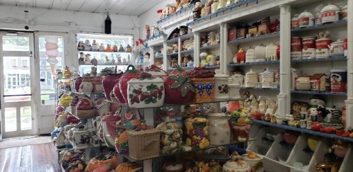 A cozy shop filled with colorful ceramic jars, pots, and decorative items on shelves and displays.
