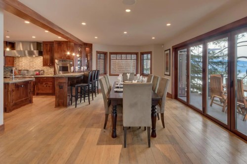 A spacious dining area with a wooden table, chairs, and large windows overlooking a scenic view.