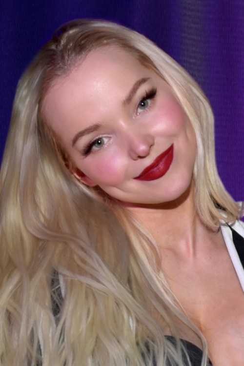 A smiling woman with long blonde hair and red lipstick, set against a purple background.