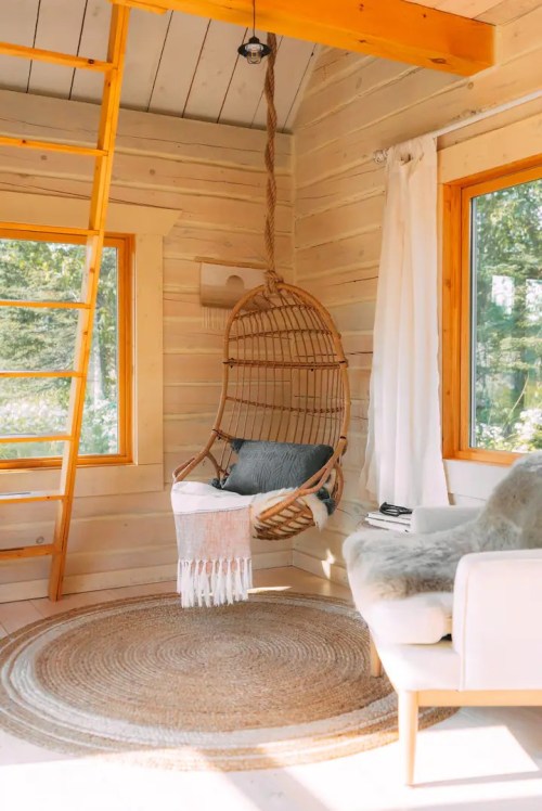Cozy interior with a hanging chair, a soft rug, and large windows letting in natural light.