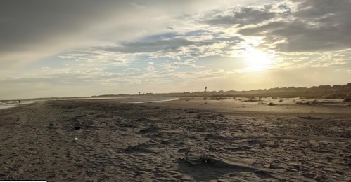 A serene beach scene at sunset, with soft clouds and gentle waves lapping at the shore.