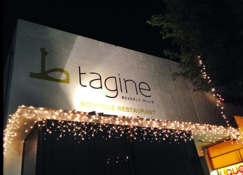 Sign for "b tagine" boutique restaurant in Beverly Hills, illuminated with string lights at night.