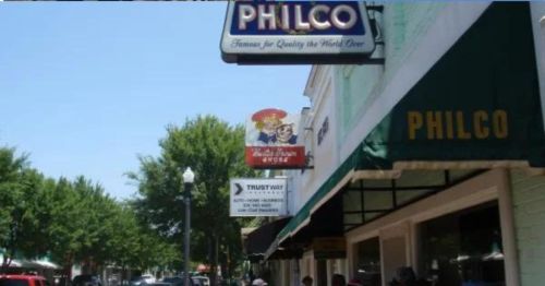 A street view featuring the Philco sign and nearby storefronts under a clear blue sky.