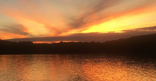 A serene sunset over a lake, with vibrant orange and pink hues reflecting on the water's surface.