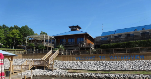 A wooden building with a blue roof, surrounded by greenery, featuring a sign that says "Welcome to Watersview."