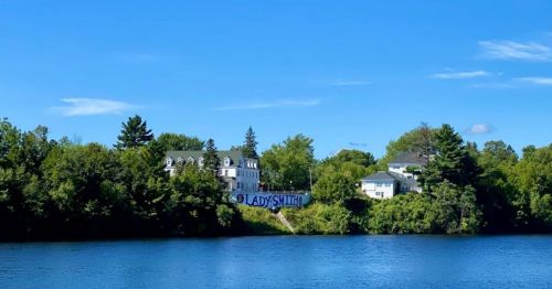 A scenic view of a river with a building labeled "Lady Smith" surrounded by trees under a clear blue sky.