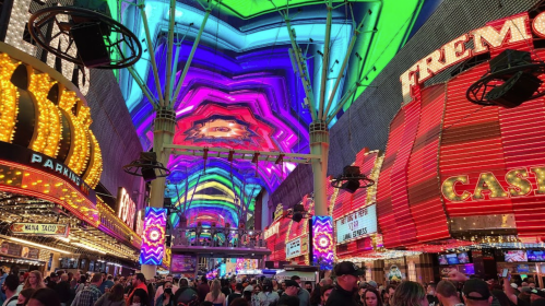 Vibrant lights and colorful patterns illuminate Fremont Street, bustling with crowds and neon signs in Las Vegas.
